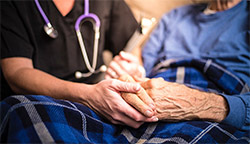 A medical worker holding the hand of an elderly person.