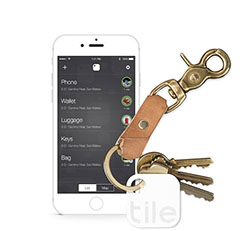 A Tile-brand tracking device attached to a keychain, next to a smartphone.