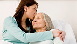 A young woman embraces an elderly woman.
