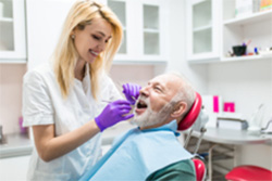 A senior man is examined by a dental professional.