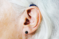 A senior ear wears a hearing aid.
