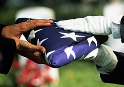 Gloves hands hand a folder American flag the family member of a fallen serviceman.